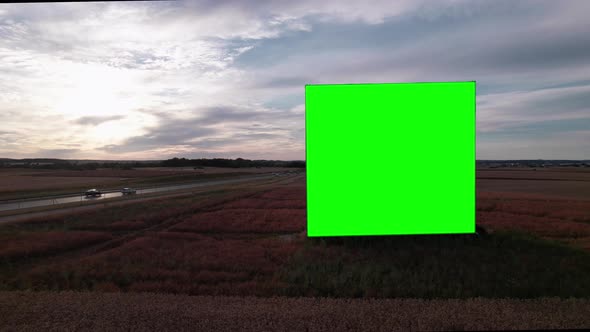 Aerial Drone Footage of Big Billboard with Green Screen near Busy Highway or Motorway at Sunset