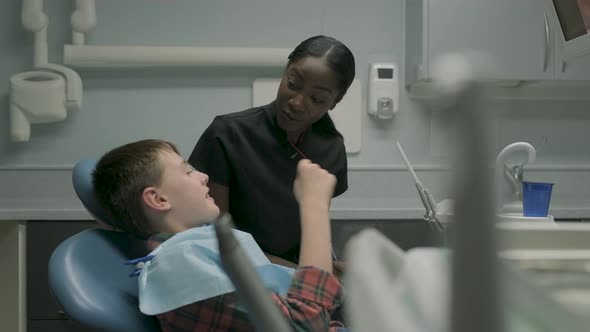 Dental assistant speaking with boy sitting on dental chair