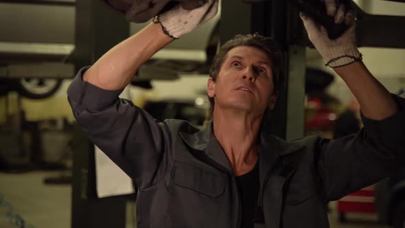 Ball joint vehicle steering maintenance by adult professional caucasian car mechanic alt