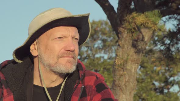 An older hiker looking through binoculars while on a scenic hike in the mountains alt