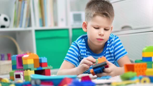 Little Boy Playing with Lots of Colorful Plastic Blocks Indoors alt
