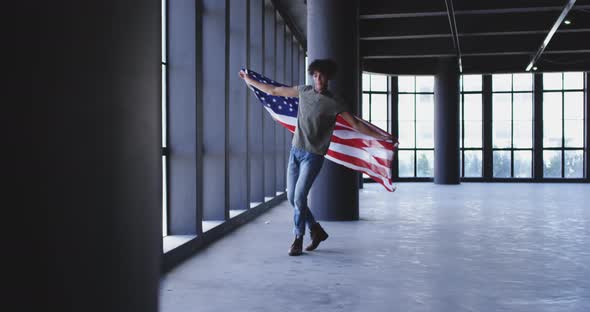 African american man dancing while holding american flag in empty parking garage alt