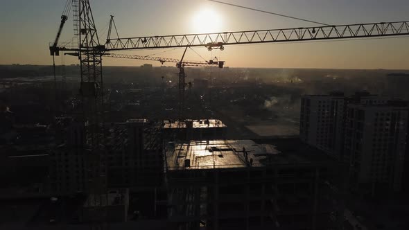 Construction Site at Sunset. Silhouette of a Construction Crane Near the Building