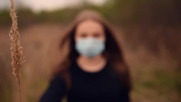Woman in a Medical Mask Covers Her Face with Dry Reeds Pandemic Covid19 Coronavirus alt