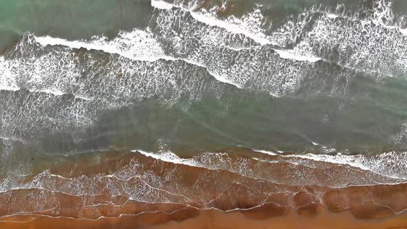 Aerial view of beach with breaking waves alt