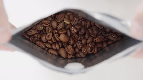 Man's Hands Opens a Package of Freshly Roasted High Quality Coffee Closeup of Arabica Coffee Beans