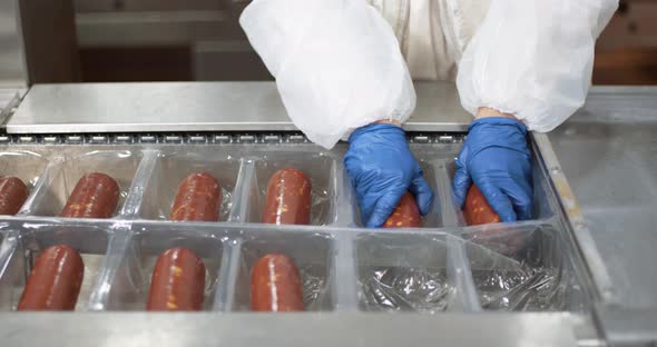 Meat Production, Woman Worker in Protective Uniforms Pack and Stack Raw Smoked Sausages, the Process alt