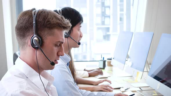 Customer care and support team wearing headphones working in call center office