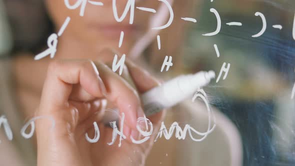 Young Attractive Female Office Worker Writing on Glass Whiteboard Close Up alt