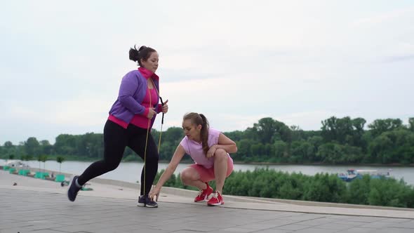 Motivated Overweight Female Doing Squats Exercises Using Fitness Tape for Weight Loss with Personal alt
