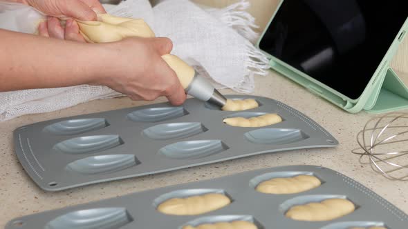 Making madeleine cookies. Person is dividing batter evenly among madeleine pan