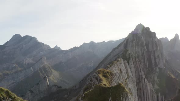 Aerial flying backwards revealing a person enjoying the view of Schäfler mountains, Appenzell, Switz alt