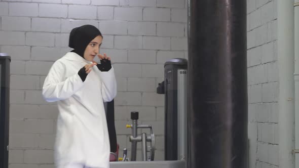 Muslim Athlete a Woman Wearing a Sports Hijab Preparing to Strike a Woman Boxing on a Pear in a alt
