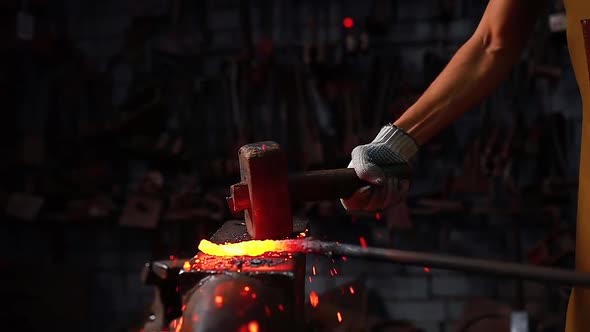 Slow Motion Close Up Hand with the Hammer of Blacksmith Man Forges a Metal Product in Dark Indoors alt