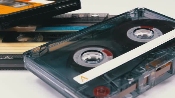 Three Vintage Audio Cassettes Rotate on White Background alt