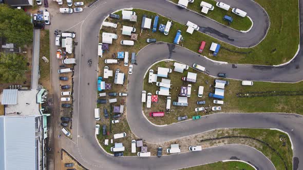 The Drone Slowly Rotates Over a Winding Road with a Green Curb and Cars on It alt