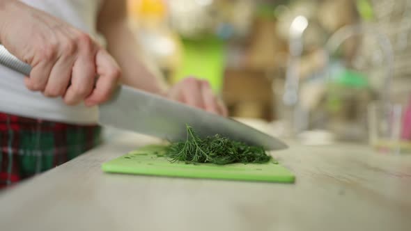 Crop Man Chopping Herbs on Cutting Board in Kitchen
