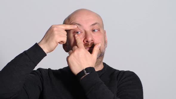 Funny mature man plays with his eyes in front of the camera alt