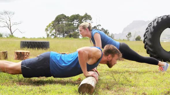 Fit man and woman doing pushup during obstacle course alt