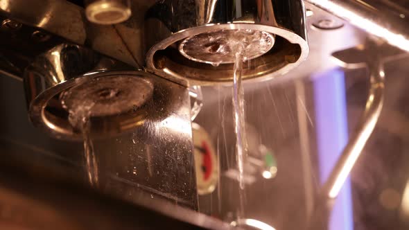 Pouring coffee stream from professional machine in cup. Water flow for cleaning a filter holder