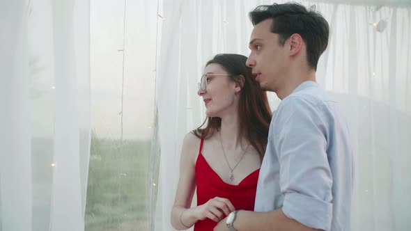 Young Pretty Couple Stand Near the Panoramic Window in the Cafe