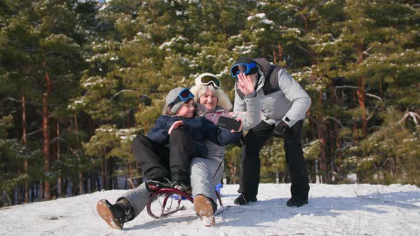 Outdoor Activities an Elderly Woman with a Man and a Grandson Sit on a Sled and Communicate Via