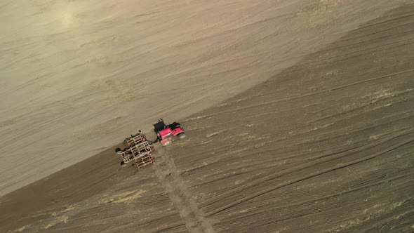 Tractor Pulls the Disc Harrow in Preparation for Sowing. Aerial View alt