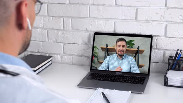 Doctor Wears Medical Coat in Hospital Advises Patient Online Video Call Laptop alt