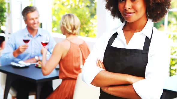 Portrait of smiling waitress standing with arm crossed alt