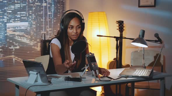 Multiracial Female Journalist Doing Online Interview on the Computer in Home Recording Studio alt
