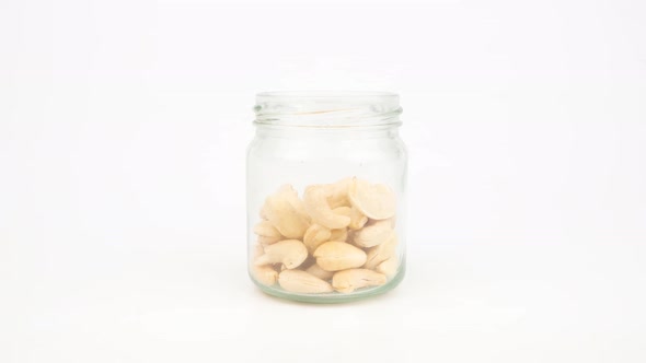 Stop motion animation Cashew nuts in a glass jar on white background.