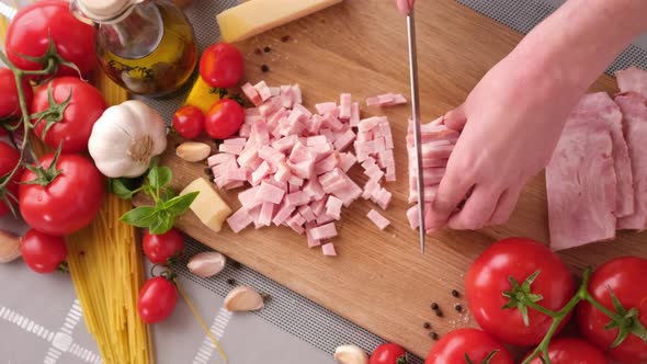 Making Pasta Carbonara Slicing Traditional Pancetta Bacon Into Pieces on a Wooden Cutting Board with alt