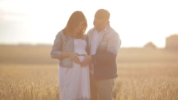 Portrait of Young Pregnant Couple in Field