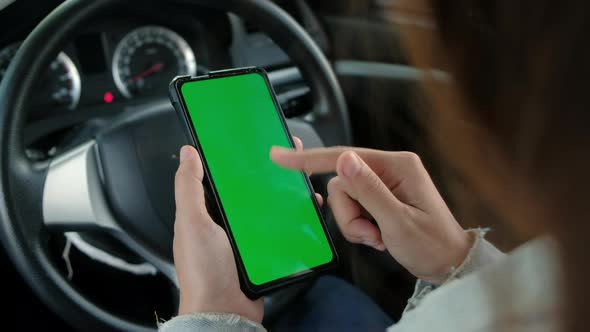 Asian woman sitting in a car using mobile phone with green mock-up screen chroma key