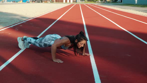Athletic Woman Doing Pushups in Outdoor Sports Ground alt