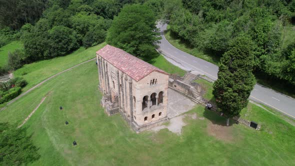 Aerial view of Santa Maria del Naranco aged catholic church with tourists visiting it. alt