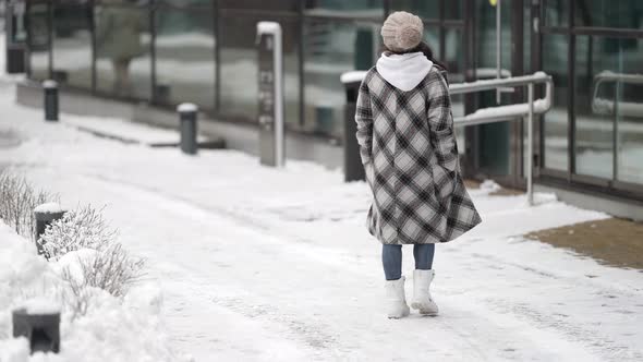 A Happy Young Darkhaired Woman in Round Glasses and a Plaid Coat Walks in the City on a Frosty alt