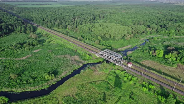 Metal Structure Railway Bridge Over a Small River and the Trees of a Forest alt