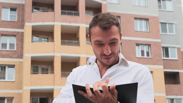 Closeup of an Enthusiastic Businessman Laughing Through a Notebook alt