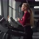 Athletic woman wearing headphones does cardio in gym on treadmill, side view. Sporty woman runs - VideoHive Item for Sale