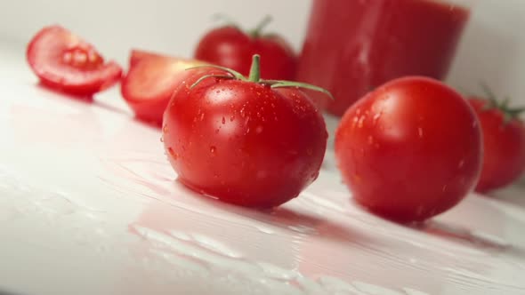 Two Ripe Tomatoes Fall On A Table, Splashing Drops. Fresh Tomato Juice On A Background