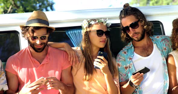 Group of hipster friends looking on their smartphone alt