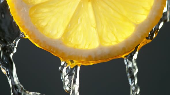 Super Slow Motion Macro Shot of Flowing Water From Lemon Slice on Black Background at 1000Fps alt