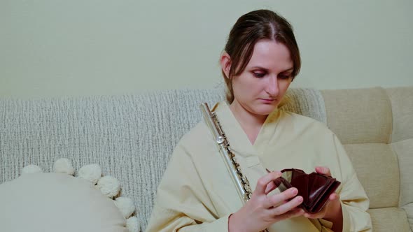 Woman musician with empty wallet no money at home on sofa in living room