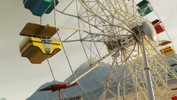 Colorful Ferris wheel spinning slowly in a mountain landscape in endless loop. alt