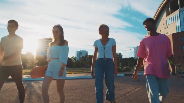 Four Difethnic Young Students Walking on Sunny Street Communicating Sharing Stories Laughing alt