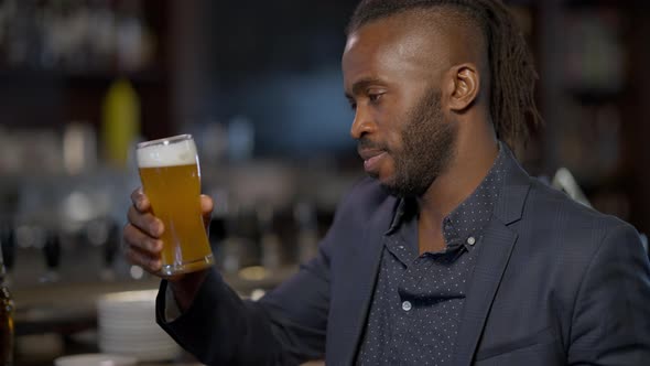 Handsome Cheerful African American Man Raising Beer Glass Winking Smiling Looking at Camera alt