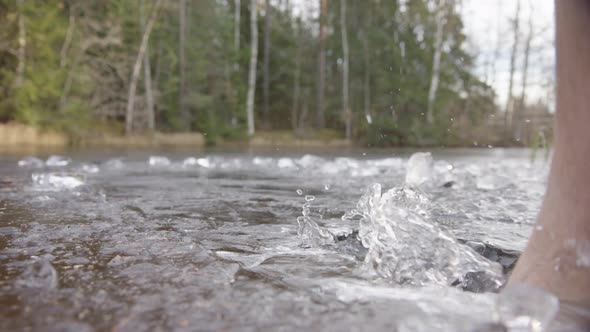 SLOW MOTION - Bare feet smash through the ice to enter the lake for bathing alt