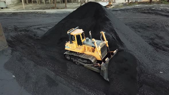 Yellow bulldozer moves the coal. Extractive industry. Aerial view. alt