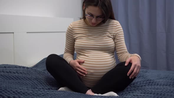 Young Pregnant Woman with Glasses Stroking Her Belly alt